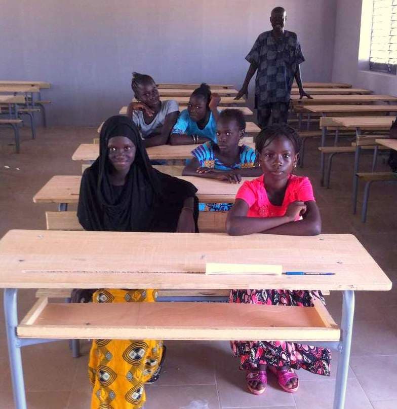 New bright classroom with solid walls, proper desks and smiling students